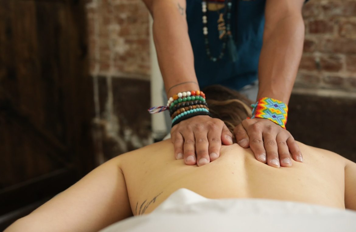 Ryan's hands giving a back massage in a brick-walled treatment room