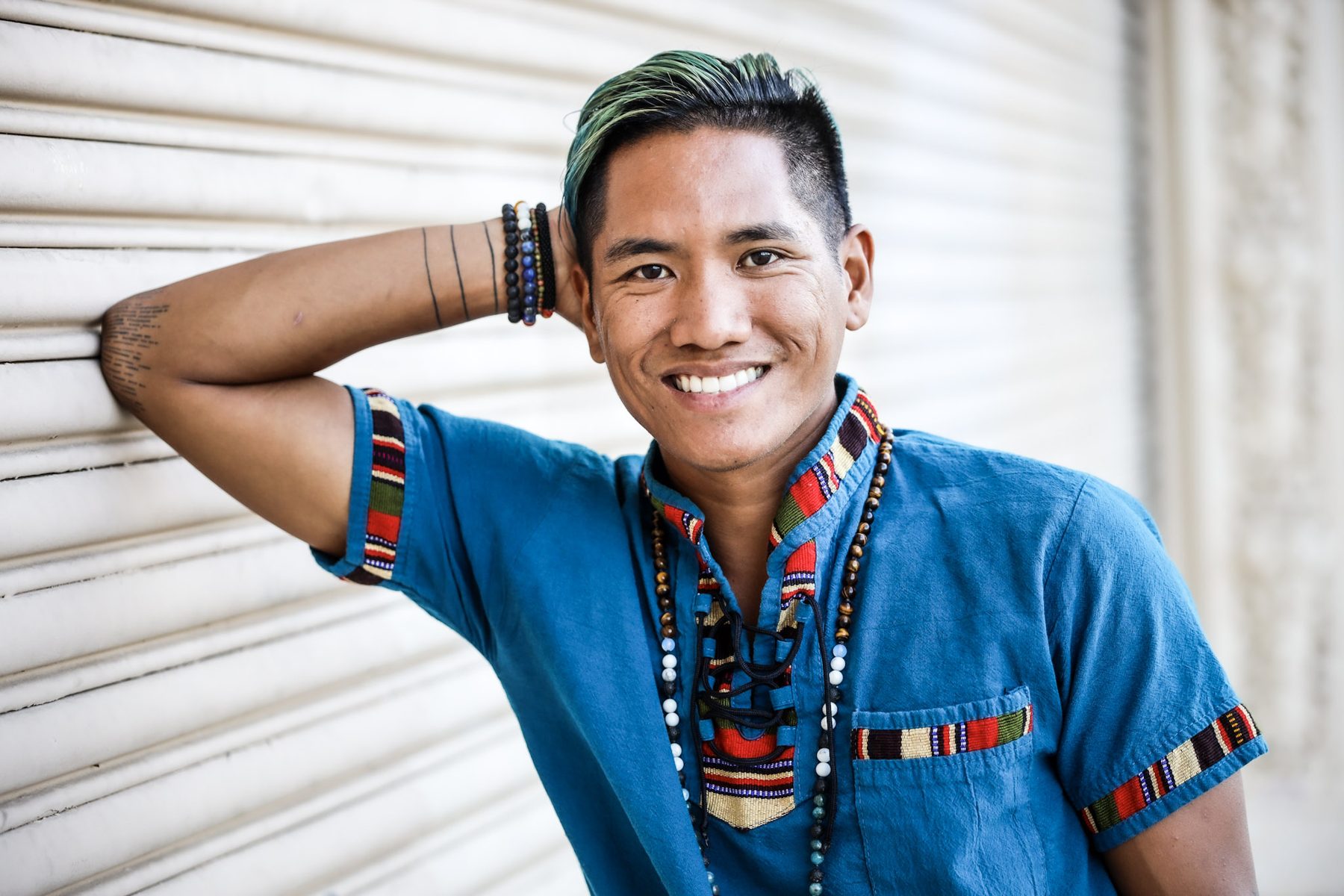 Ryan smiling, leaning on a wall with his hand behind his head